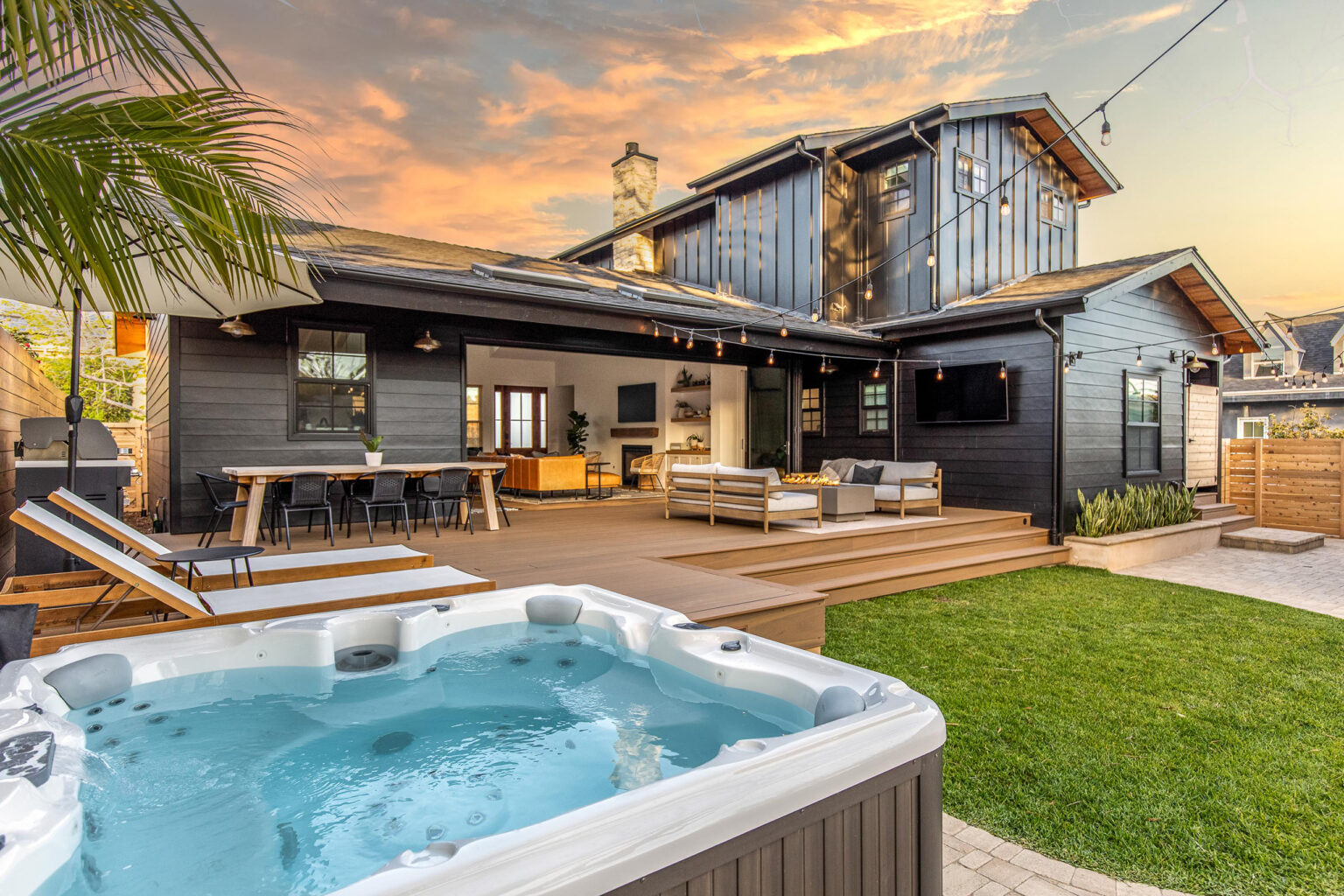 The back of the house at dusk, with the hot tub, deck and lawn
