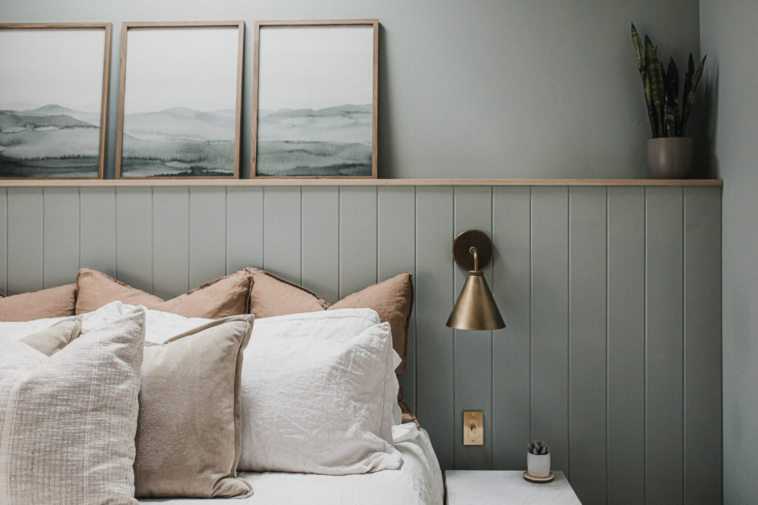 The primary bedroom, with its panelled wall and brass reading sconces