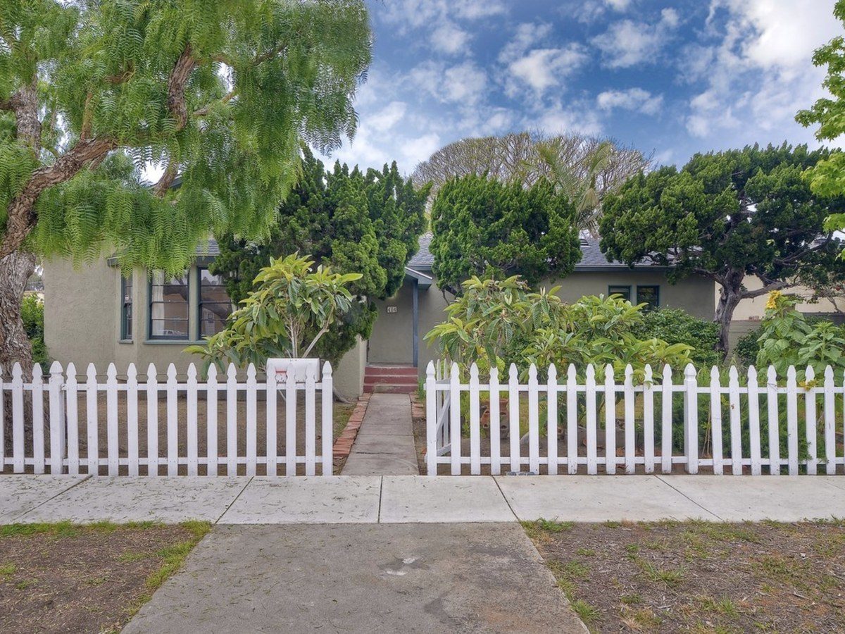 The original 1939 stucco bungalow with a white picket fence, before the remodel
